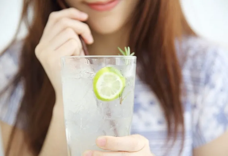 A breastfeeding mother holding a large glass of water with lemon