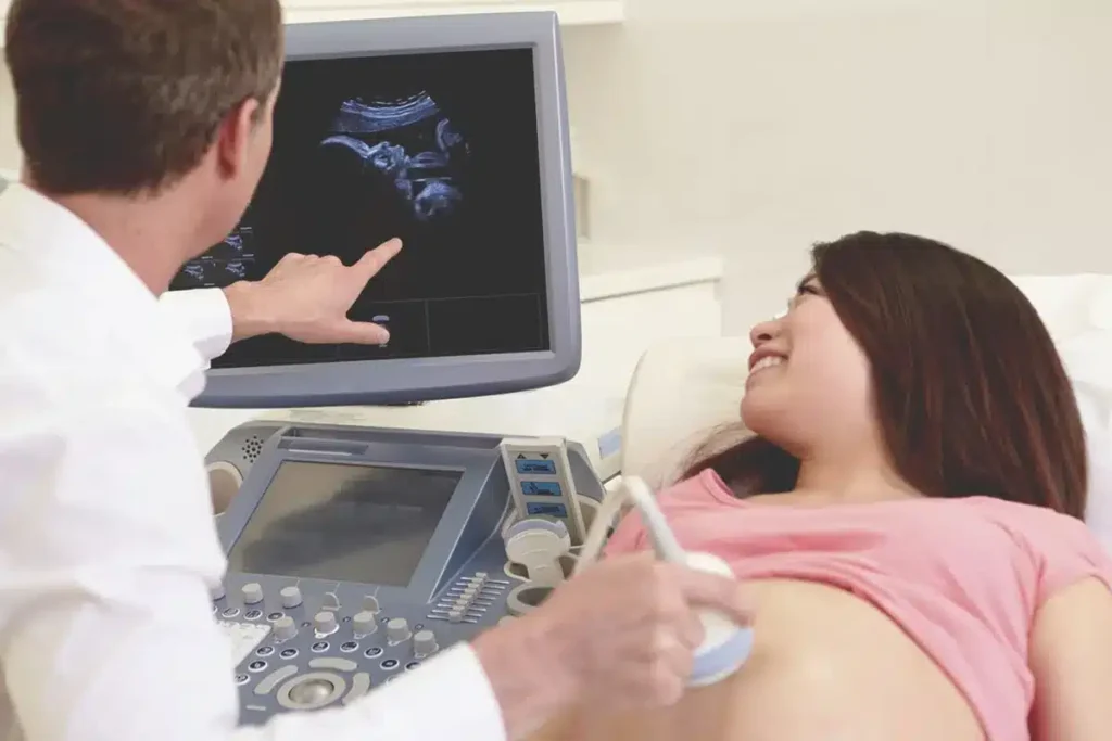 A calm, professional image of a doctor and pregnant person reviewing an ultrasound screen together, symbolizing collaborative care and monitoring