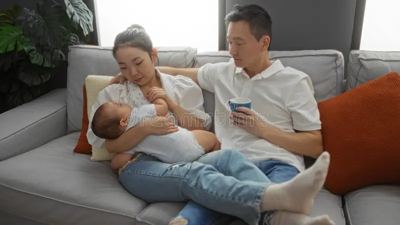 A grandparent holding a newborn while sitting on a couch