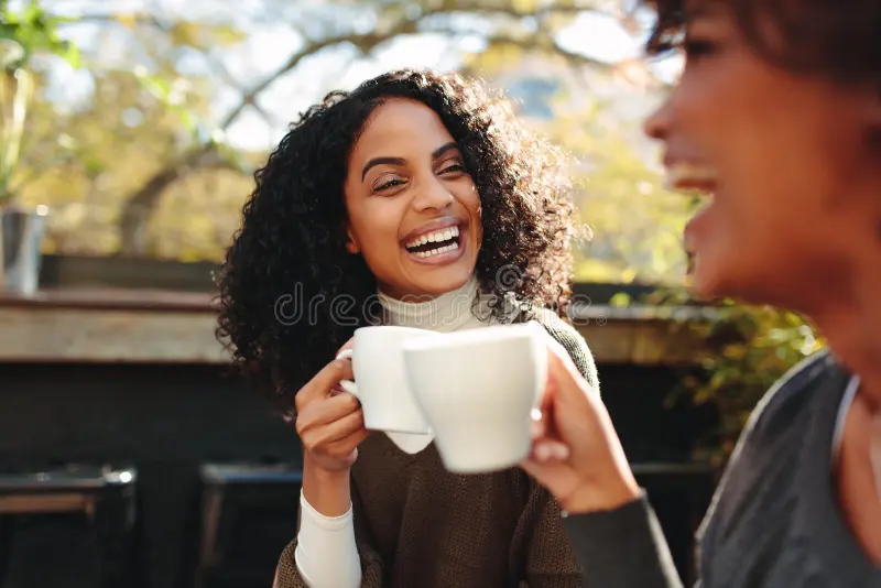 A mother laughing with a friend at a coffee shop