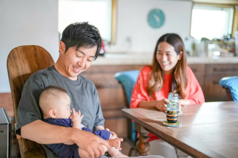 A new mother and father sharing a cup of coffee on their porch while their baby sleeps