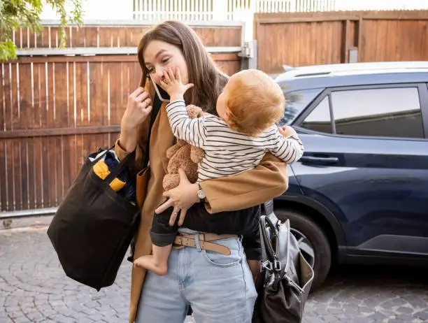 A new mother holding her baby while standing at the front door,