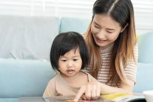 A new mother practicing self-care by reading a book alone while her partner handles the baby in another room