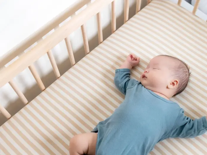 A peaceful sleeping baby in a crib with properly fitted mattress and sheet, soft lighting, creating a calm, reassuring image