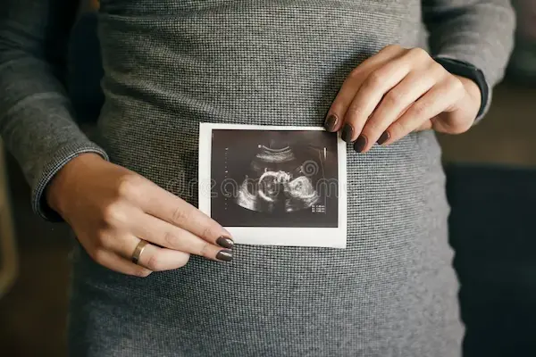 A person's hand gently holding a printed ultrasound image, focusing on the connection and emotion