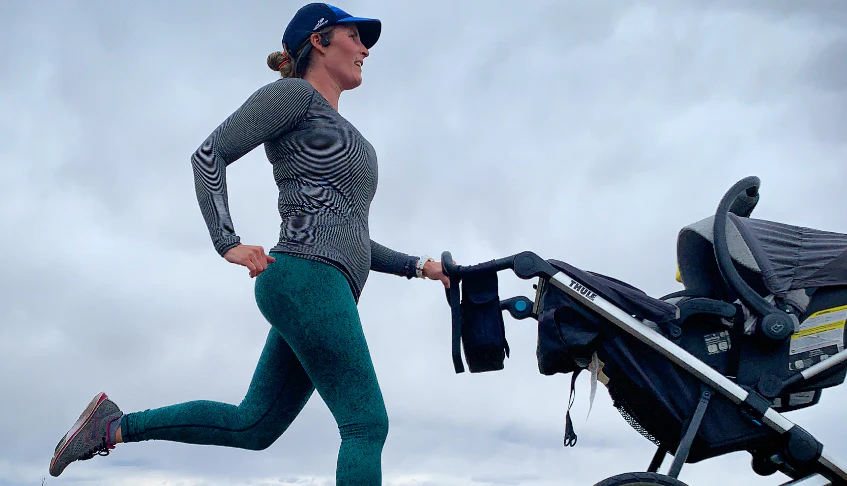 A postpartum woman confidently jogging on a peaceful path