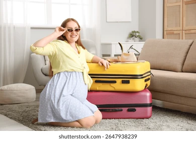 A pregnant woman smiling while zipping up a suitcase