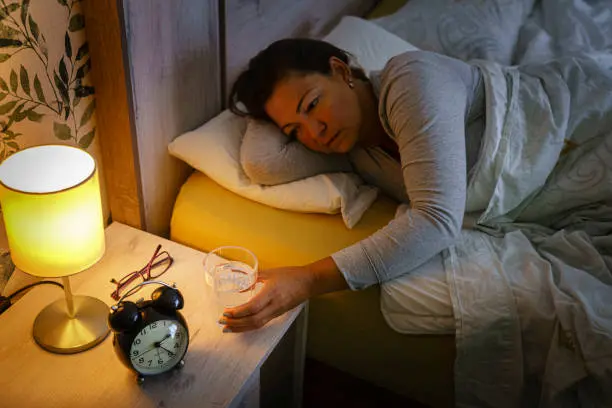 A simple, serene still-life of a bedside table with a glass of water