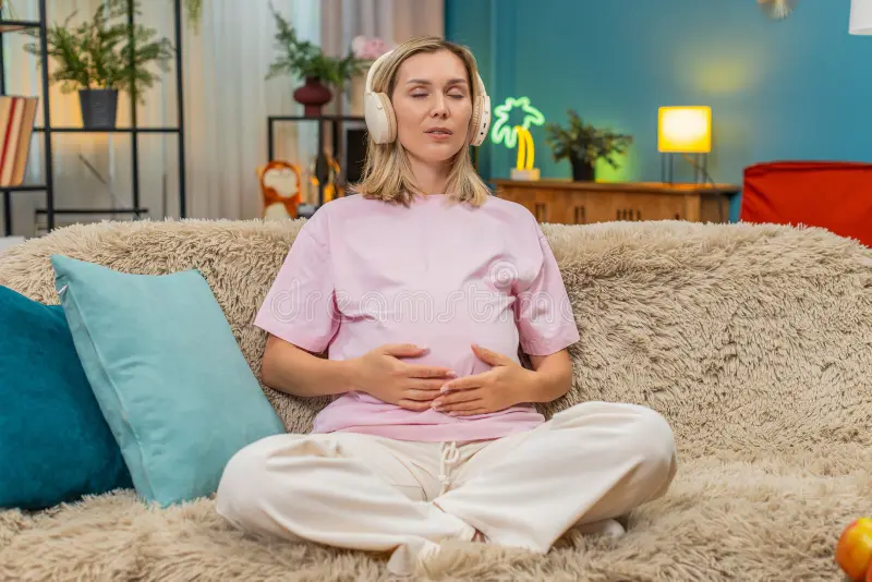 A woman sitting comfortably with her hands on her lower belly, eyes closed, practicing deep core breathing