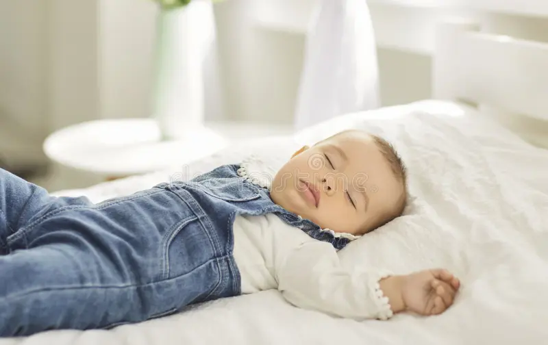 Image of a baby sleeping peacefully on their back in a safe sleep space