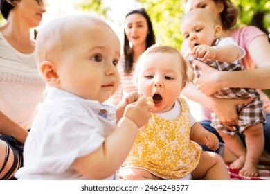 Image of a diverse group of moms with babies sitting in a circle at a playgroup, laughing together