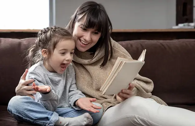 Image of a mother and toddler sitting together reading a book, both looking content
