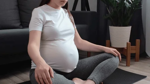 Image of a pregnant woman doing gentle prenatal stretching in a living room