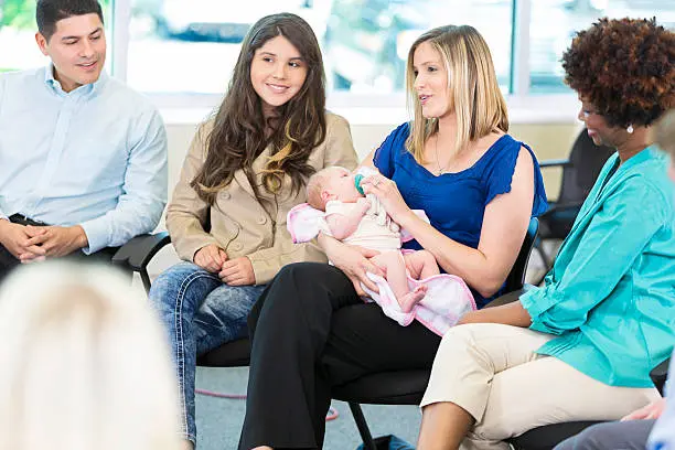 Image of diverse mothers in a support group setting, some holding babies, others listening, all engaged in healing connection